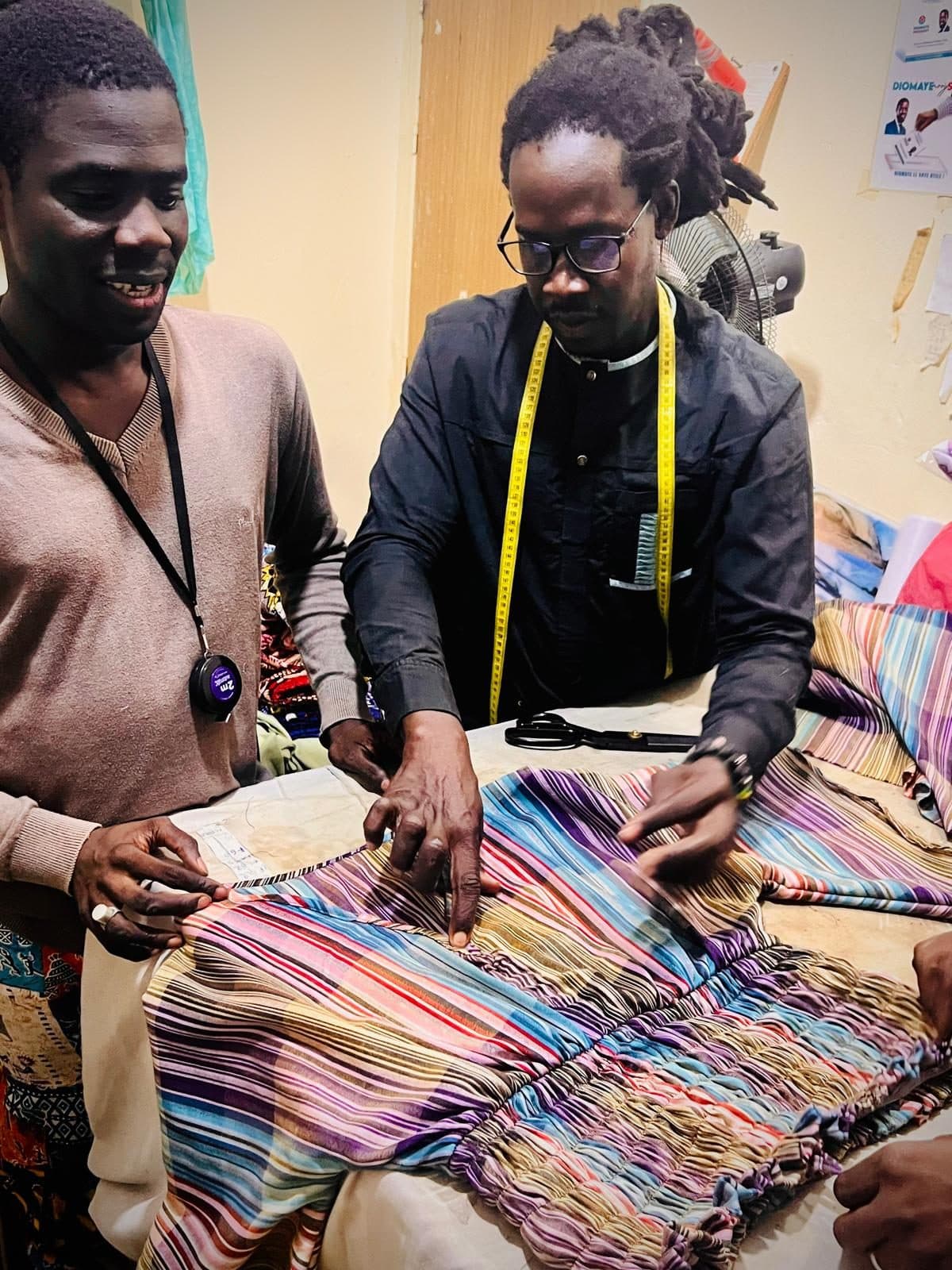 Our two tailors in their workshop in Keur Massar, Dakar, checking a new piece on the cutting table