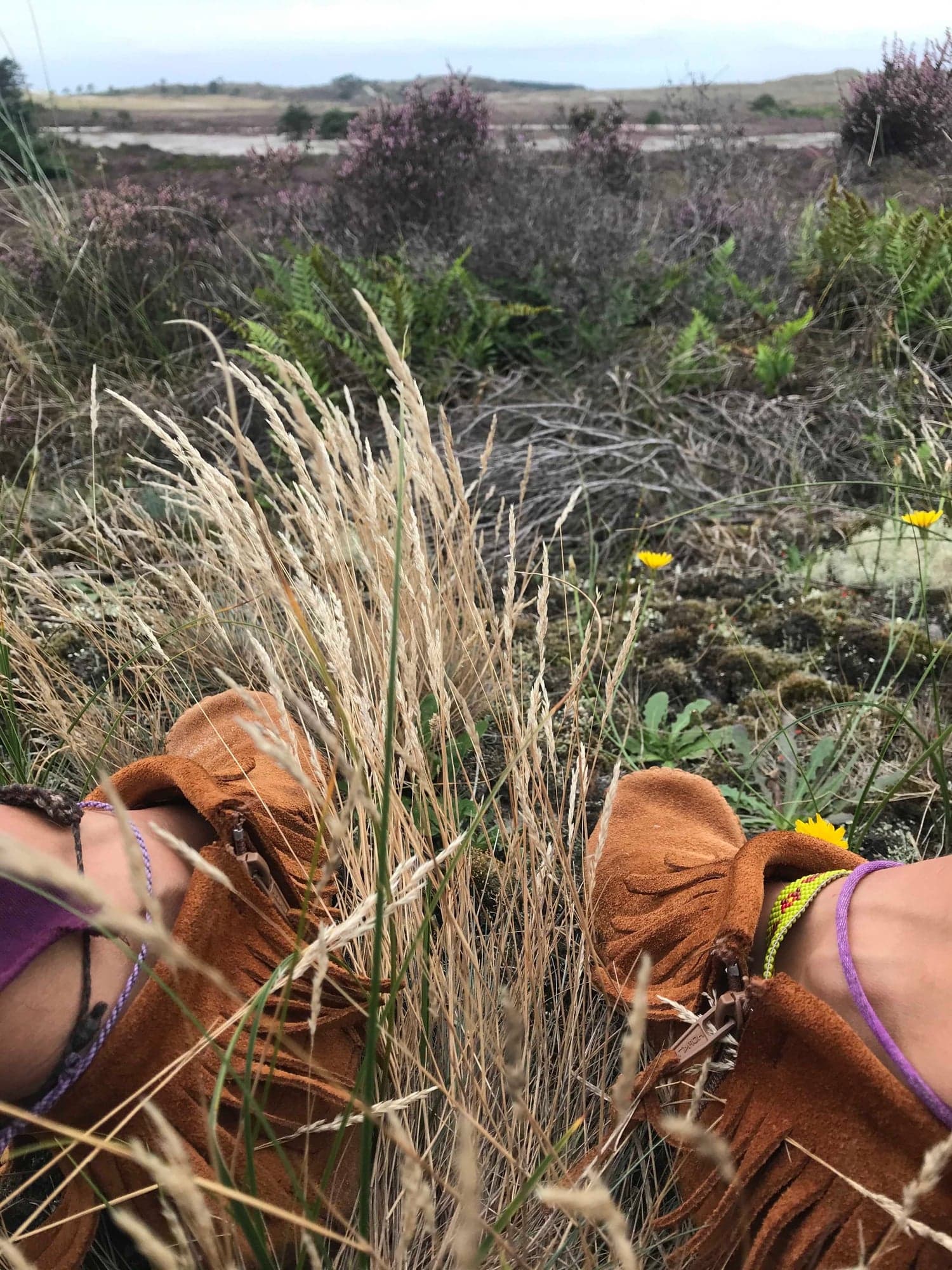 Feet in fringed leather moccasins resting in the grass of a heath